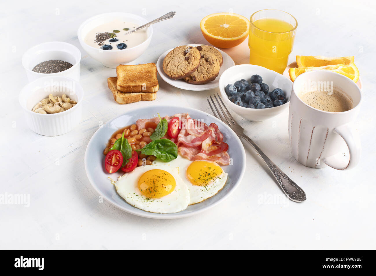 Breakfast with fried eggs, bacon, orange juice, yogurt and toasts Stock