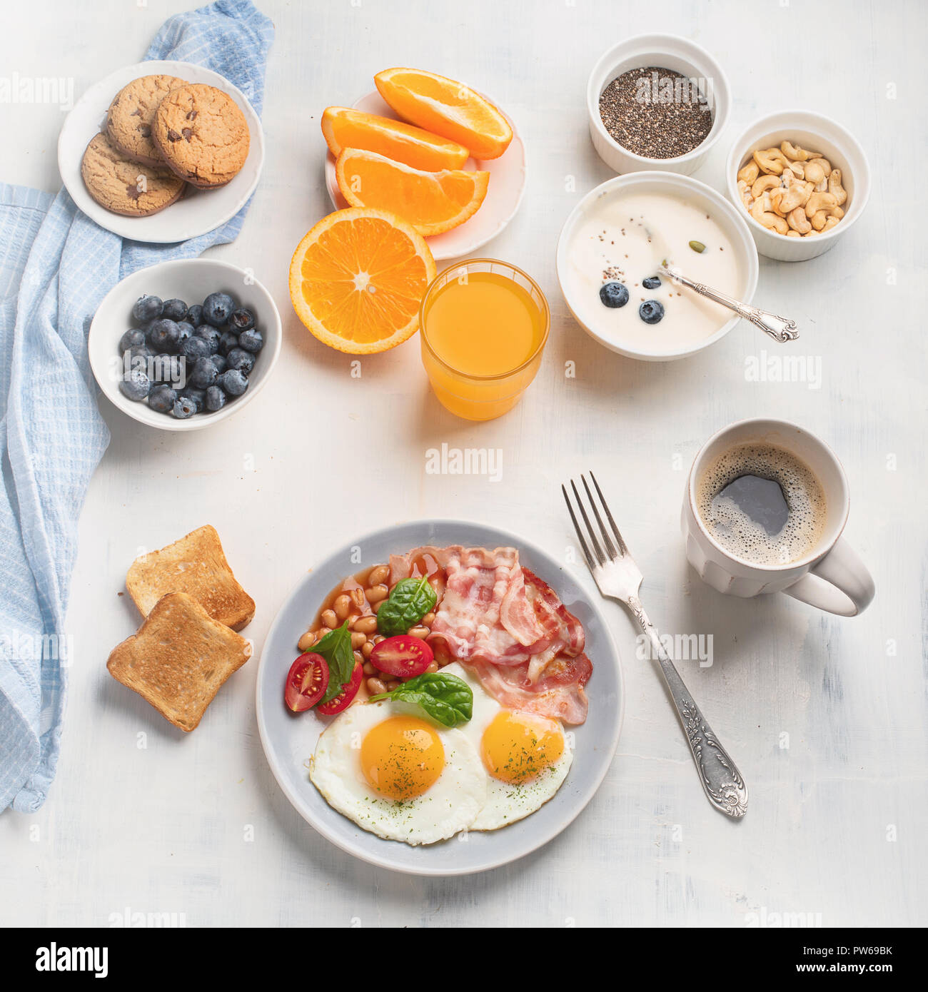 Breakfast with fried eggs, bacon, orange juice, yogurt and toasts. Flat