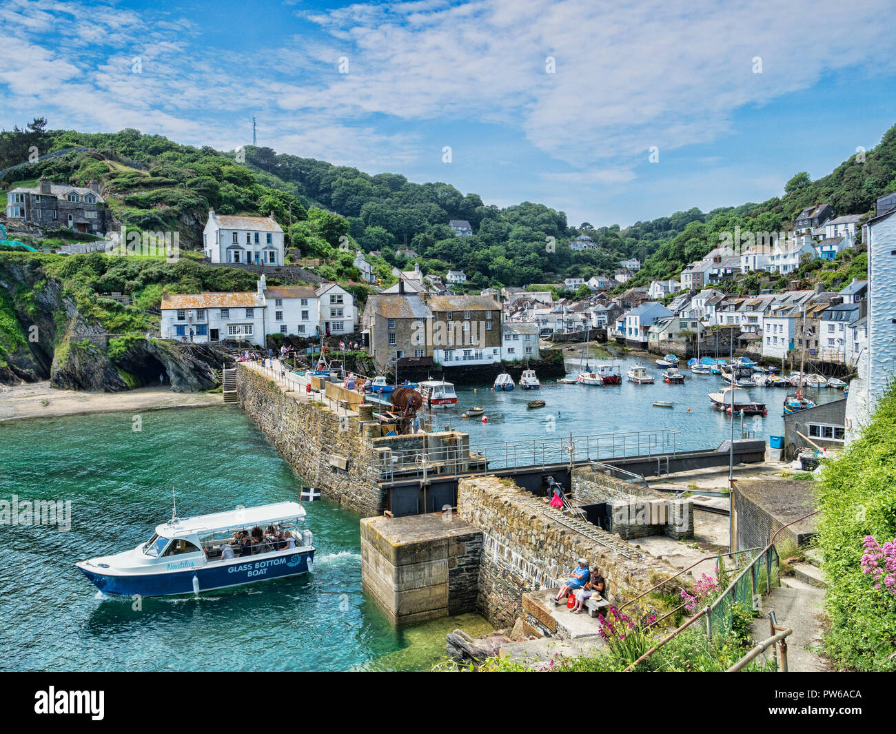 6 June 2018: Polperro, Cornwall, UK - One of the most beautiful villages in Cornwall, on an idyllic summer day, with a boat just leaving the harbour. Stock Photo