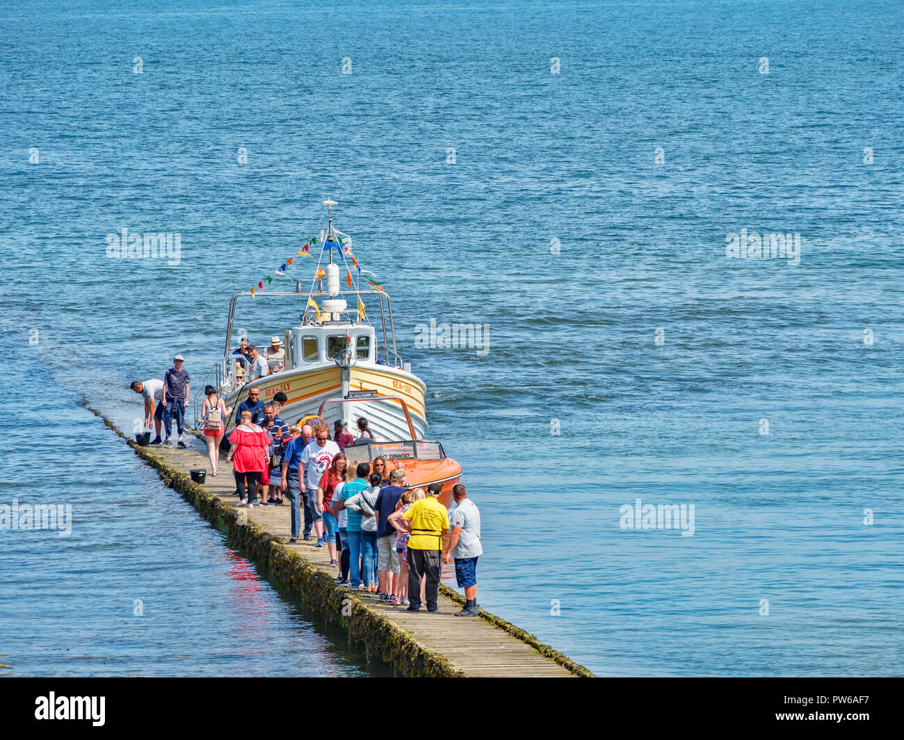 25 July 2018: Llandudno; Conwy; UK - People on the boardwalk or jetty; getting on and off the Sea Jay and a Jet Boat; for trips around the bay. Stock Photo