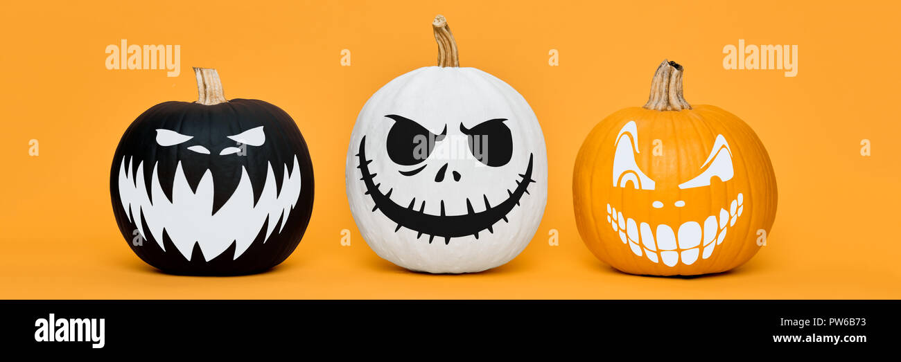 Three Spooky Halloween pumpkins with scary face expressions over orange ...