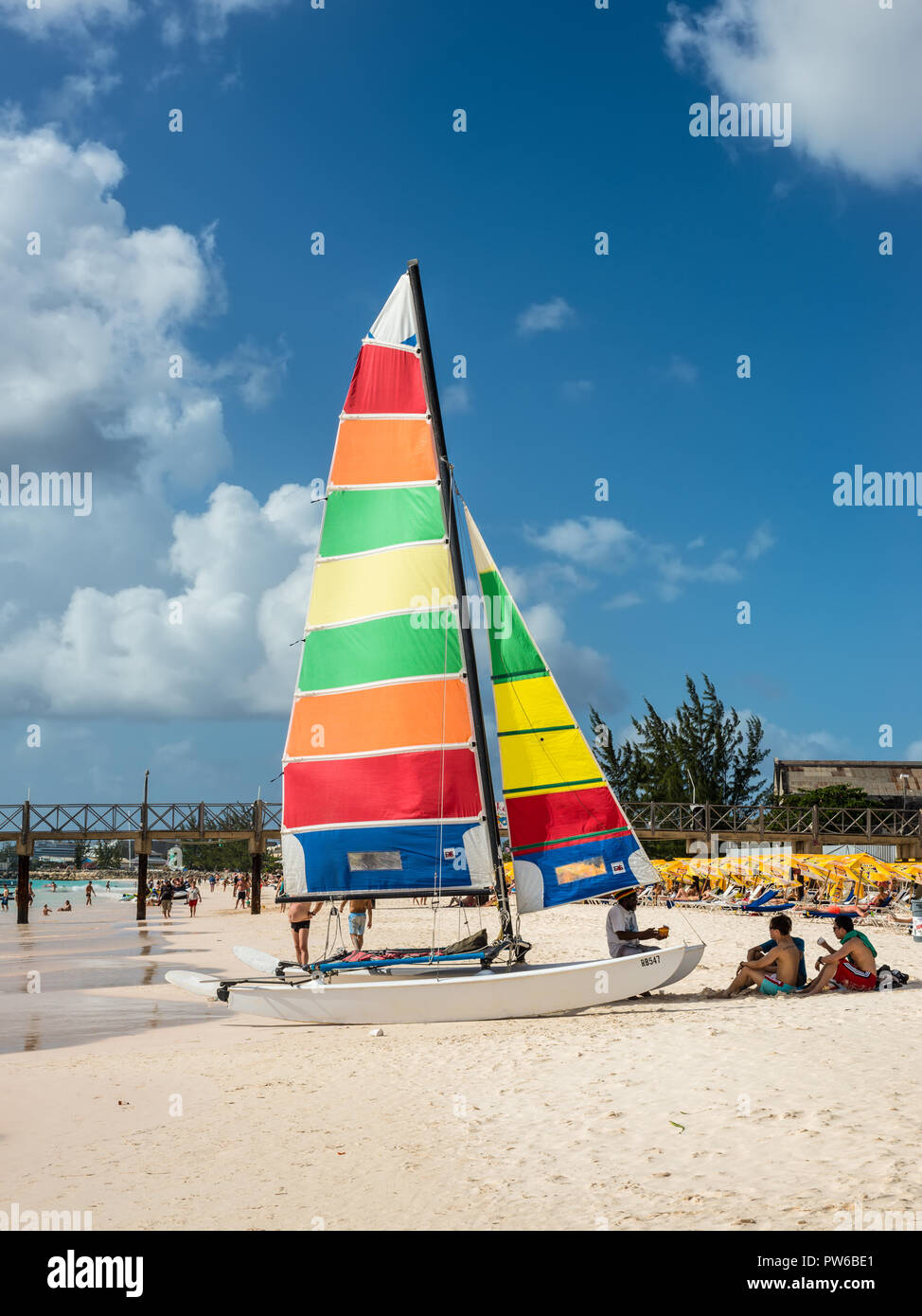 Bridgetown, Barbados - December 18, 2016: Brownes beach at ocean coast with people and colorful sail on a yacht at sunny day in Bridgetown, Barbados. Stock Photo