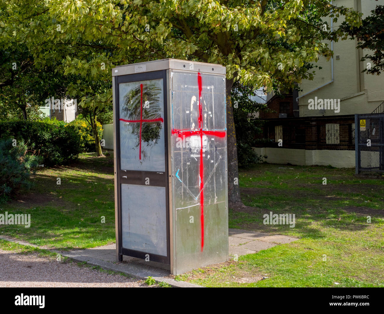 A red cross sprayed onto a phone box in the Kent coastal town of Sheerness. Stock Photo