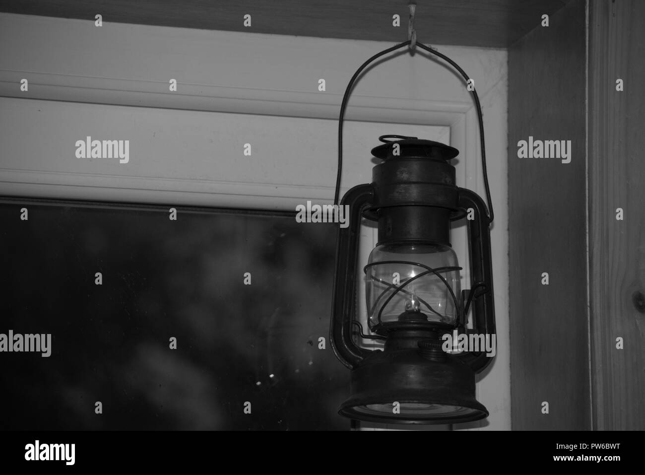 Kerosene or hurricane lamp framed in a doorway, black and white Stock