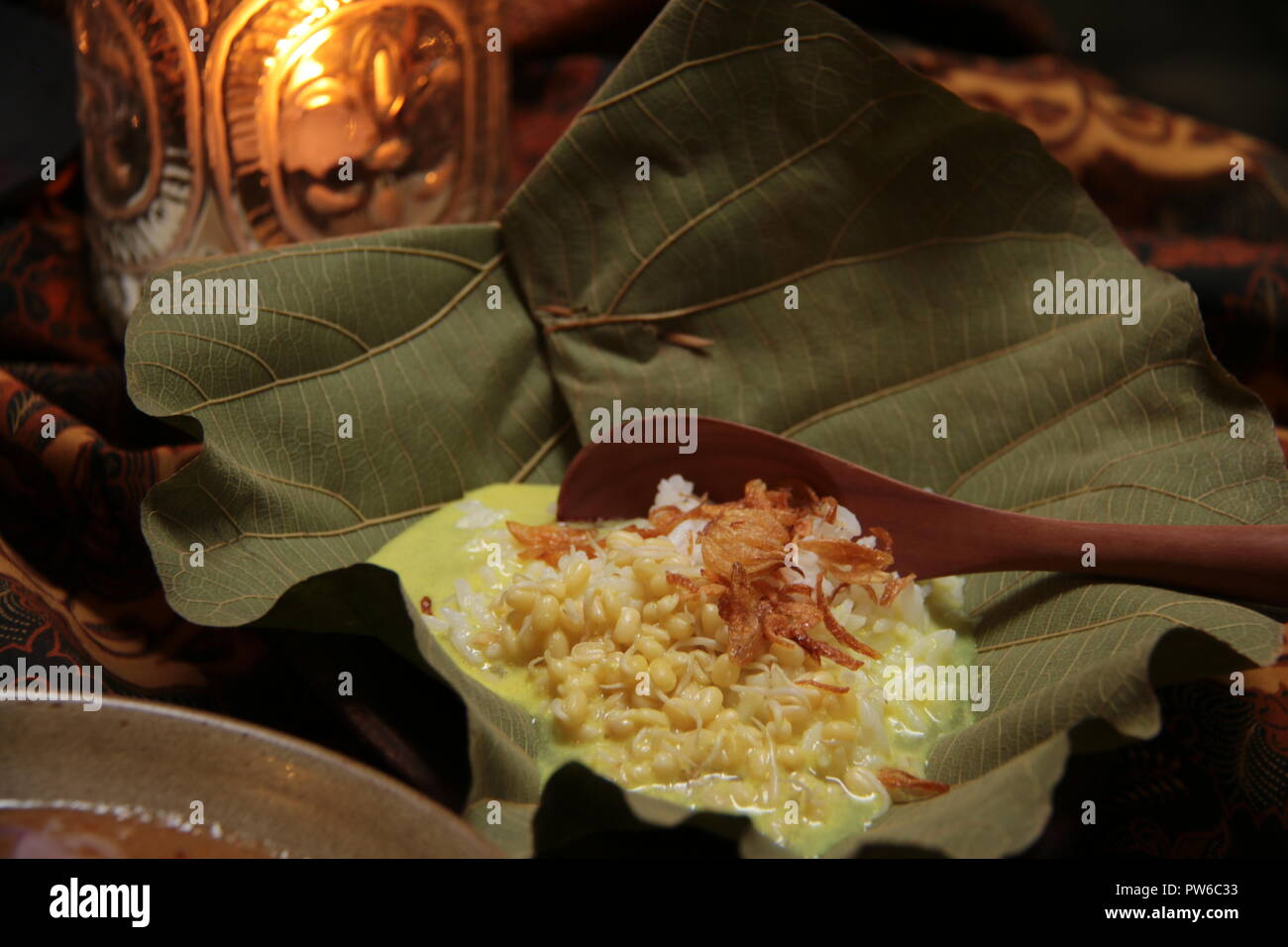 Nasi Opor or Nasi Gulai, the rice in yellow curry soup, the popular staple food for Sate Blora. Served in authentic way, in bowl made of teak leaf. Stock Photo