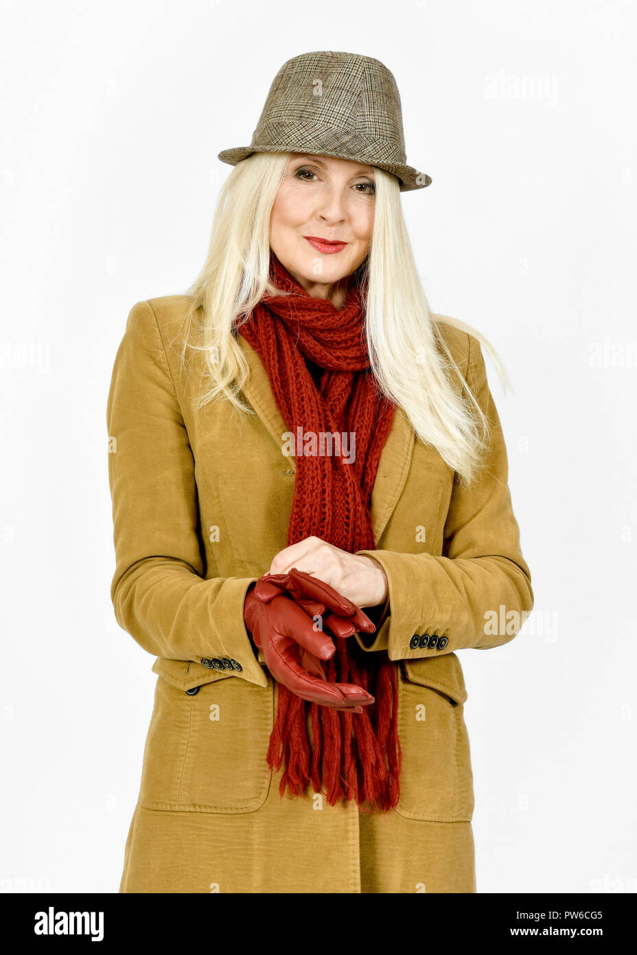 Attractive Caucasian woman in winter clothing putting a red pair of gloves on Stock Photo