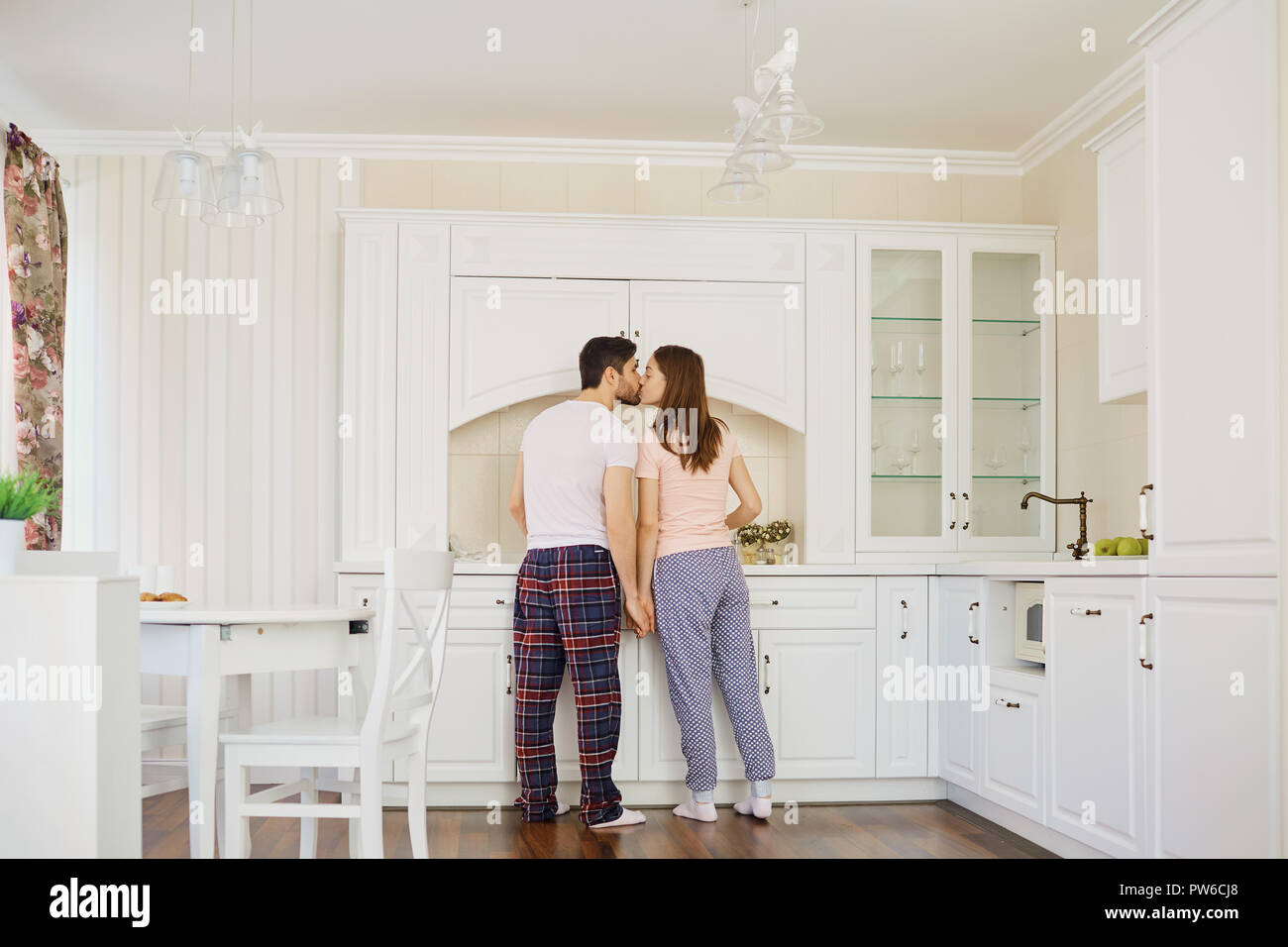 Rear view of a young couple in pajamas stand in the kitchen Stock Photo