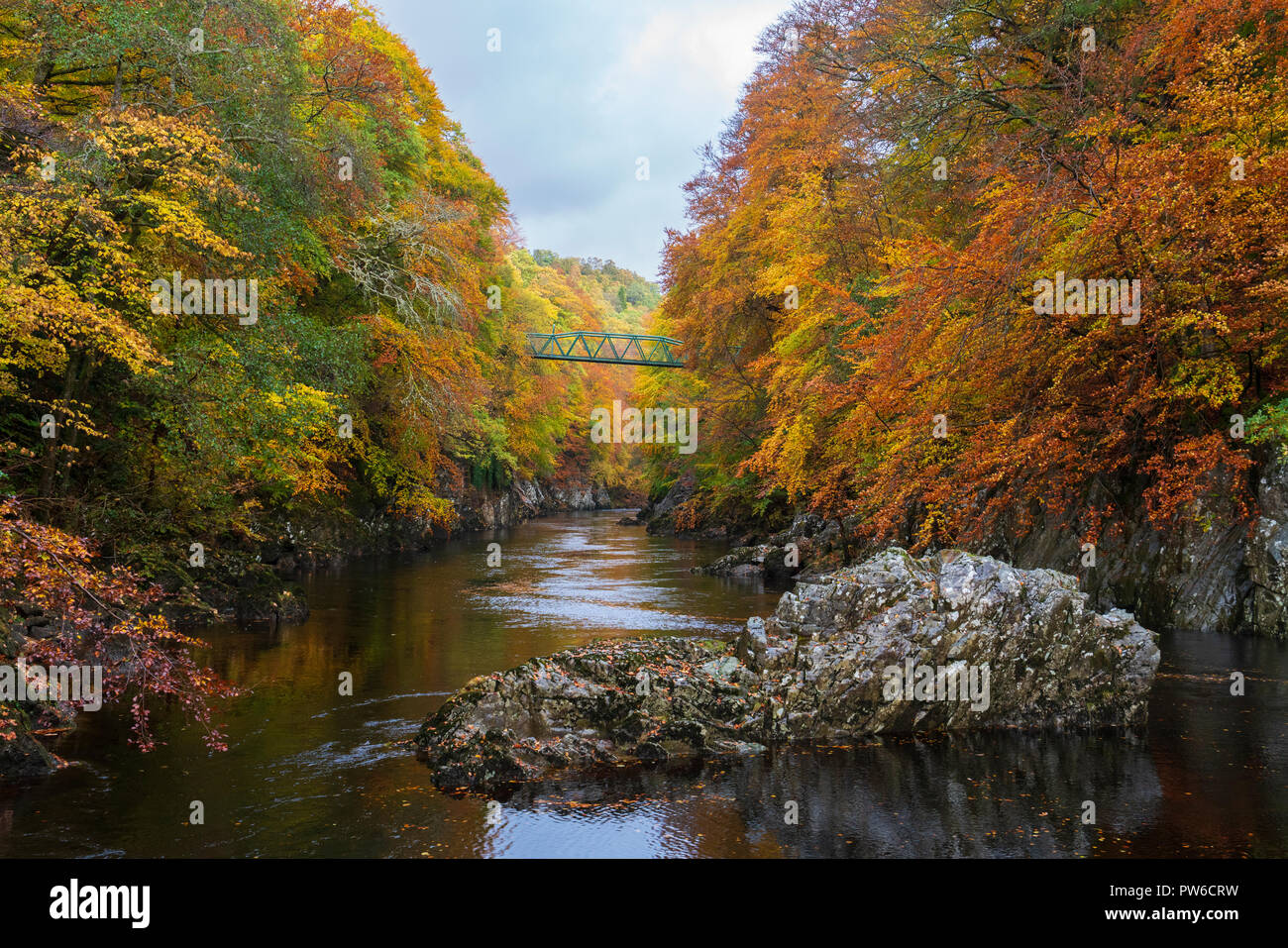 Spectacular autumn colours surround a small footbridge crossing the River Garry at Killiecrankie, the famous Perthshire beauty spot. Stock Photo