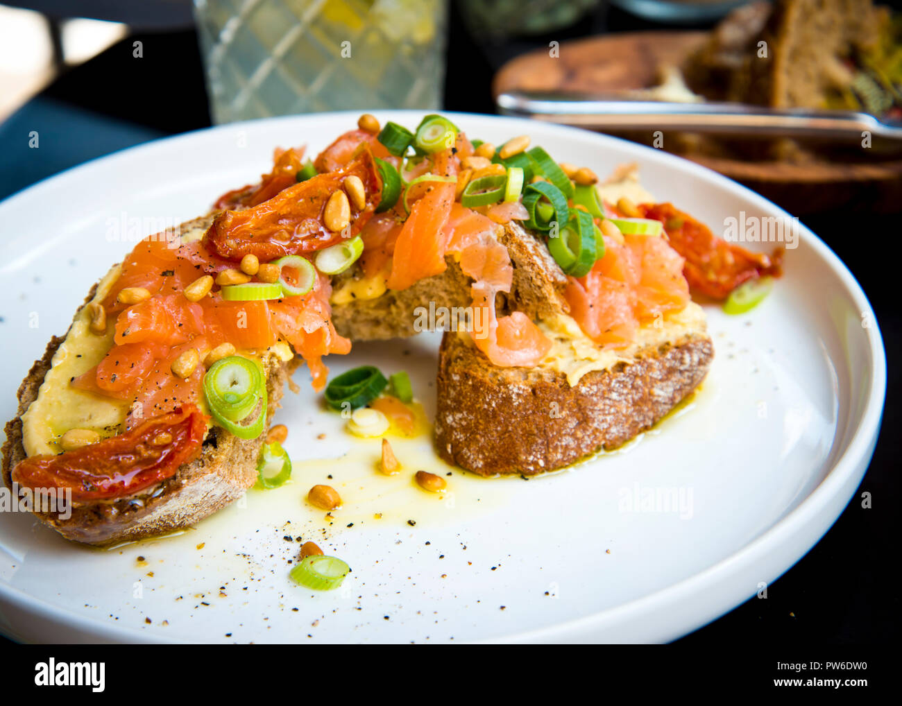 open sandwich for a good healthy option,grilled cheese on brown bread,topped with fresh salmon,chopped spring onion,sun dried tomatoes light lunch. Stock Photo