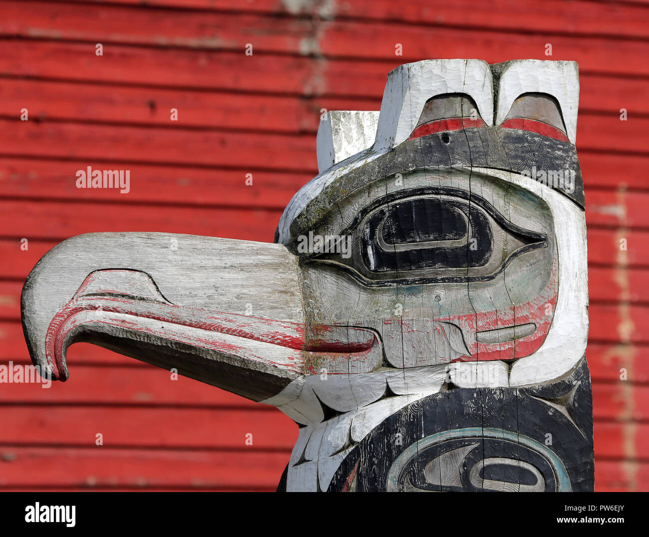 Native American bird motif totem pole with red background, Stock Photo