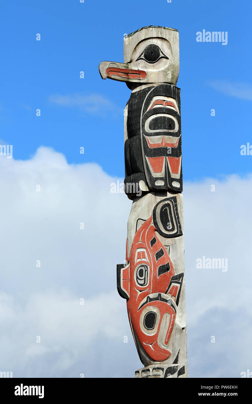 Native American bird and salmon motif totem pole with red background ...