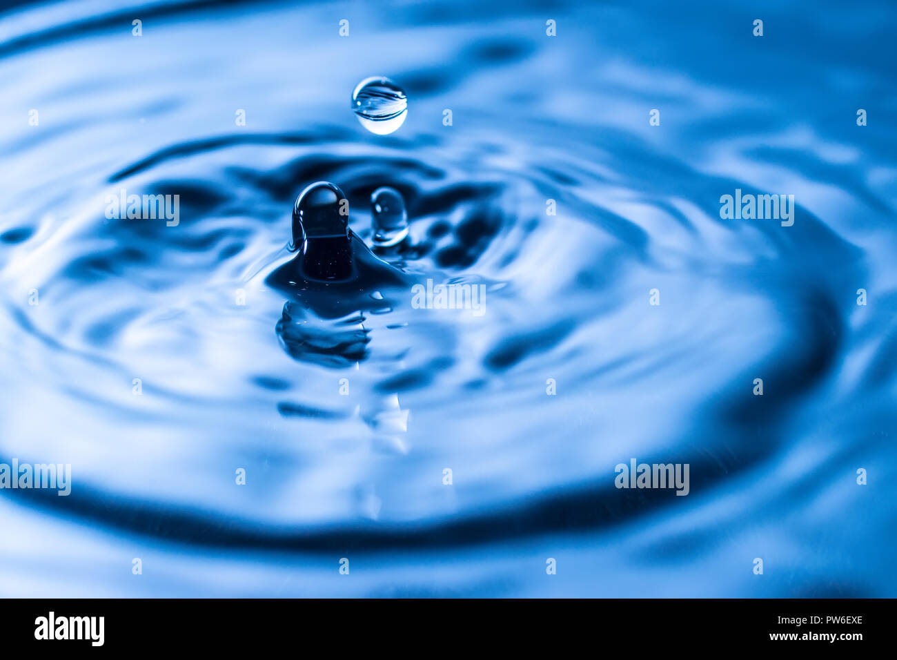 water drop splash in a glass blue colored Stock Photo - Alamy