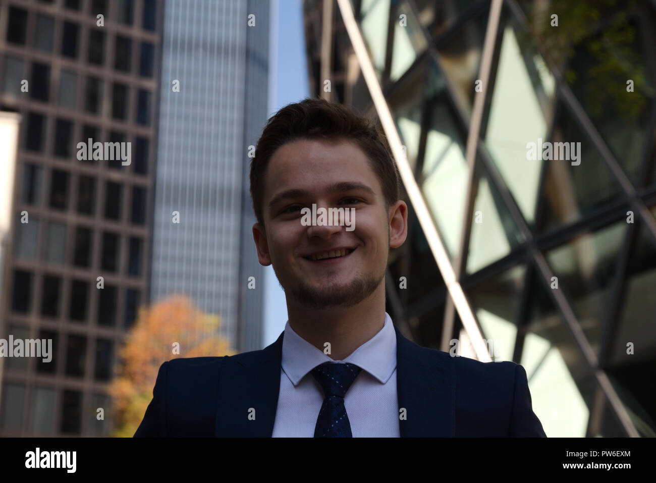 Portrait of successful smiling young business man in full suit outdoors Stock Photo