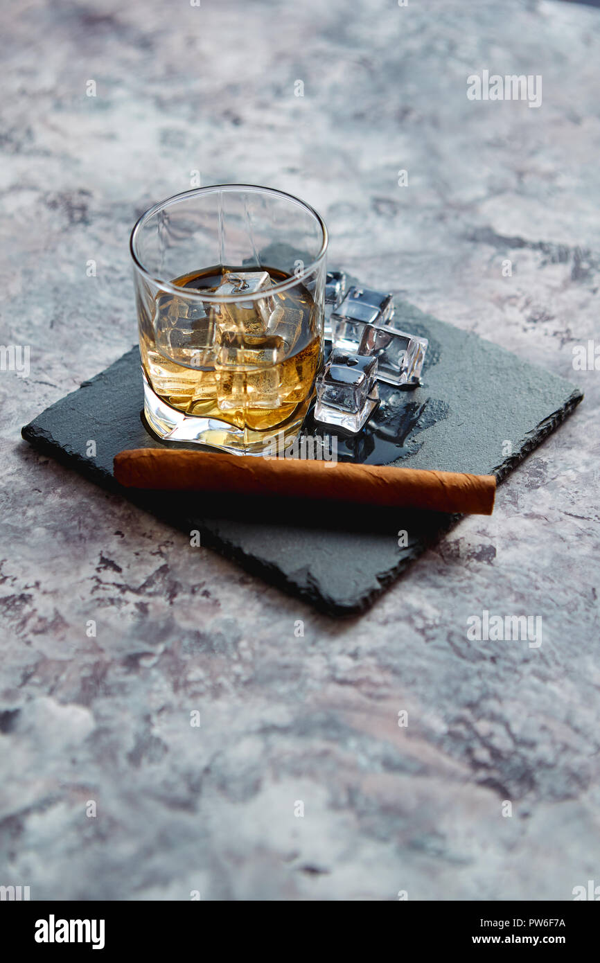 Glass of whiskey with ice cubes and cigar Stock Photo