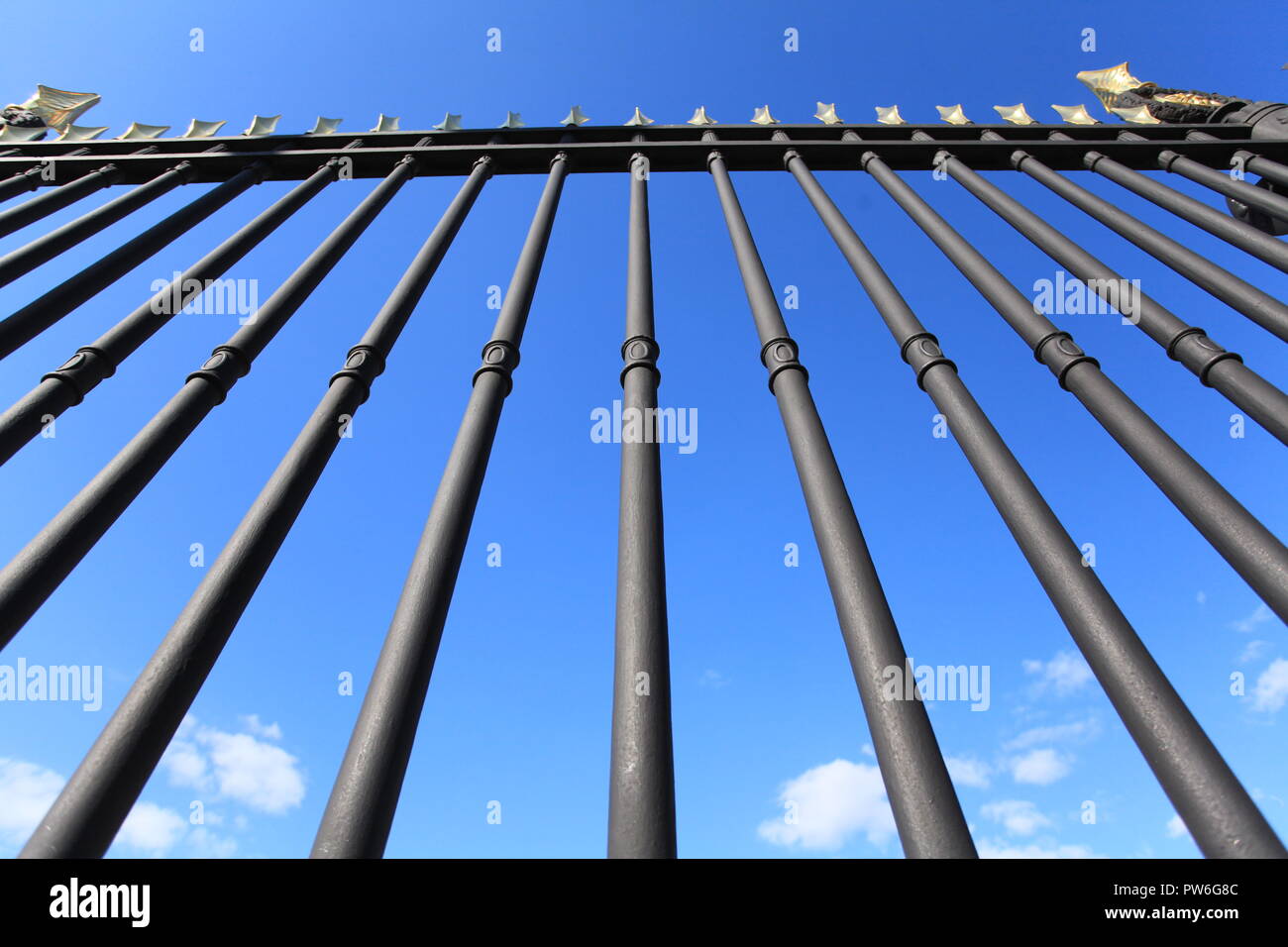 Huge black iron fence closes the blue sky Stock Photo
