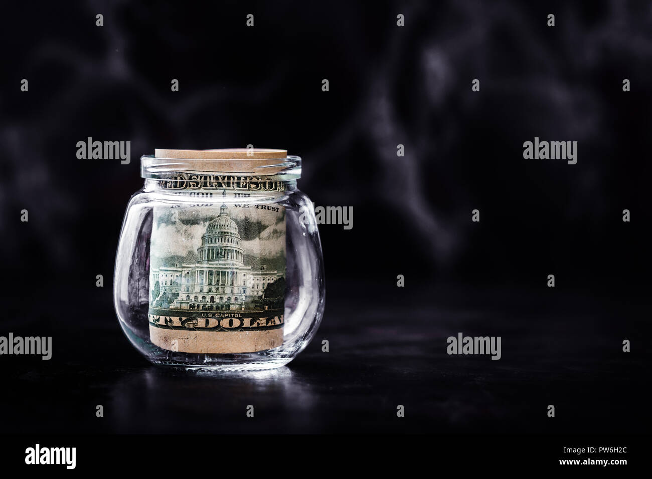 Fifty dollar banknotes rolled up in glass bottle Stock Photo