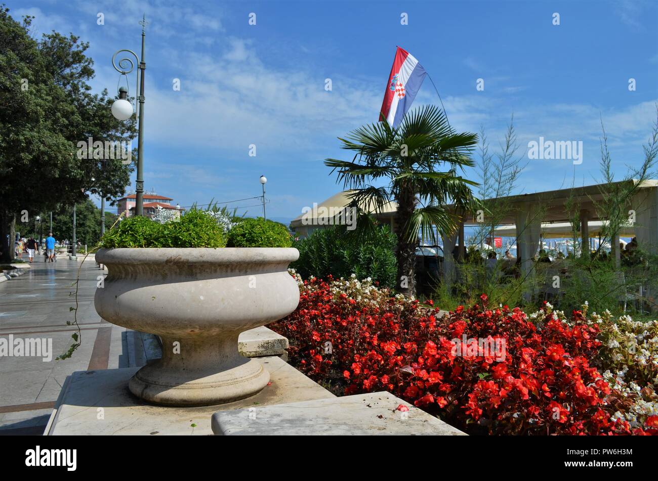 flowers and palmtrees next to a walkway made of stones in Croatia at the Mediterranean sea Stock Photo