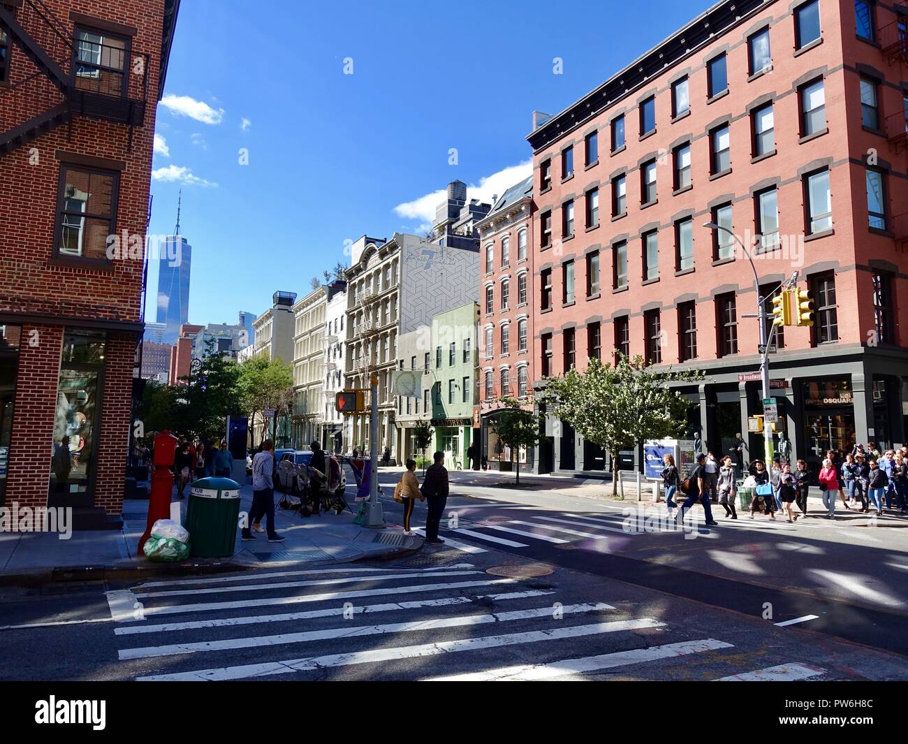 Apartment building with shops, people, with 1 World Trade Center in the background, at intersection of West Broadway and Spring St, New York, NY, USA. Stock Photo