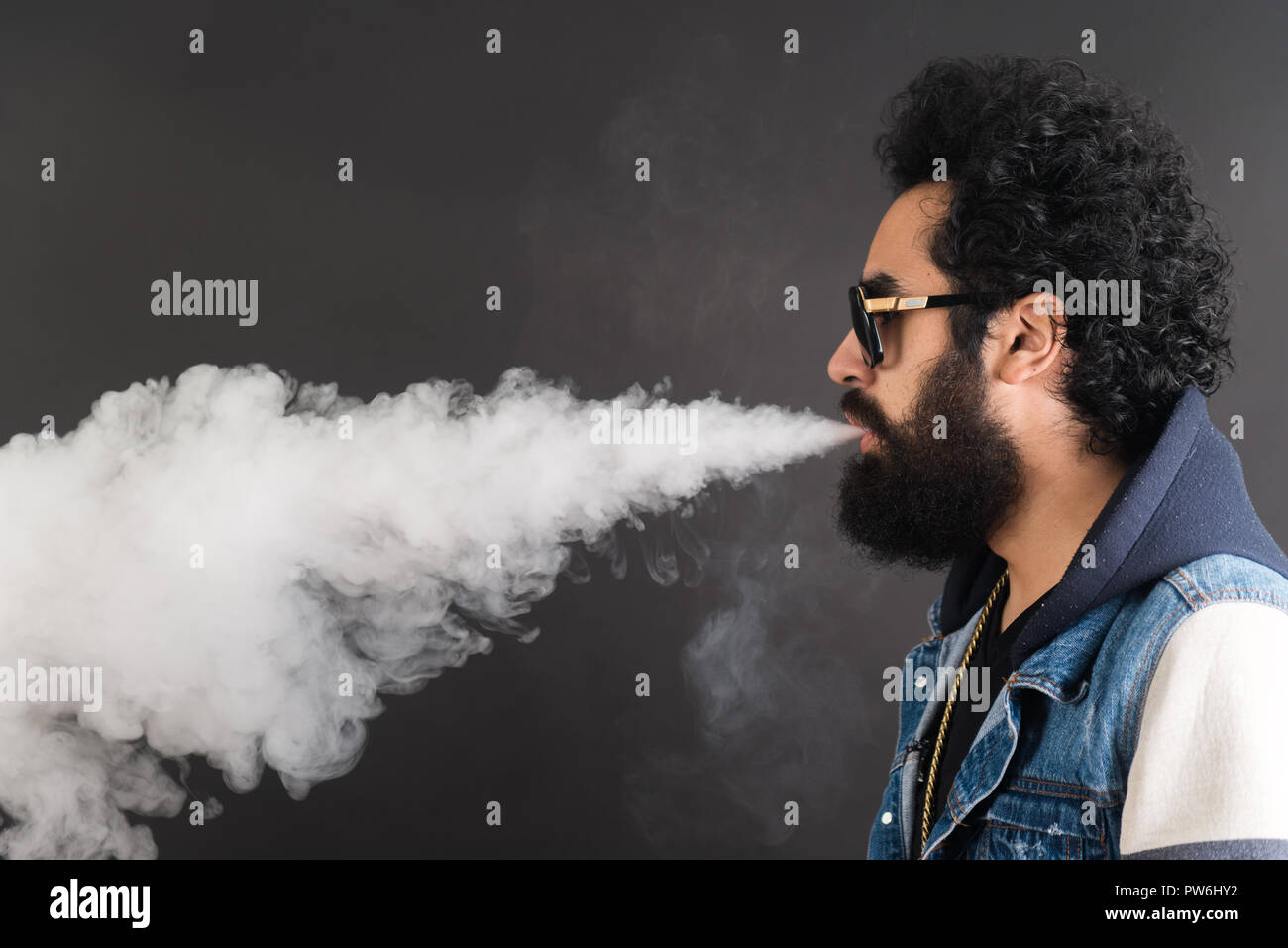 Young man vaping, studio shot. Bearded guy with sunglasses blowing a cloud  of smoke on black background. Concept of smoking and steam without  nicotine, copy space Stock Photo - Alamy