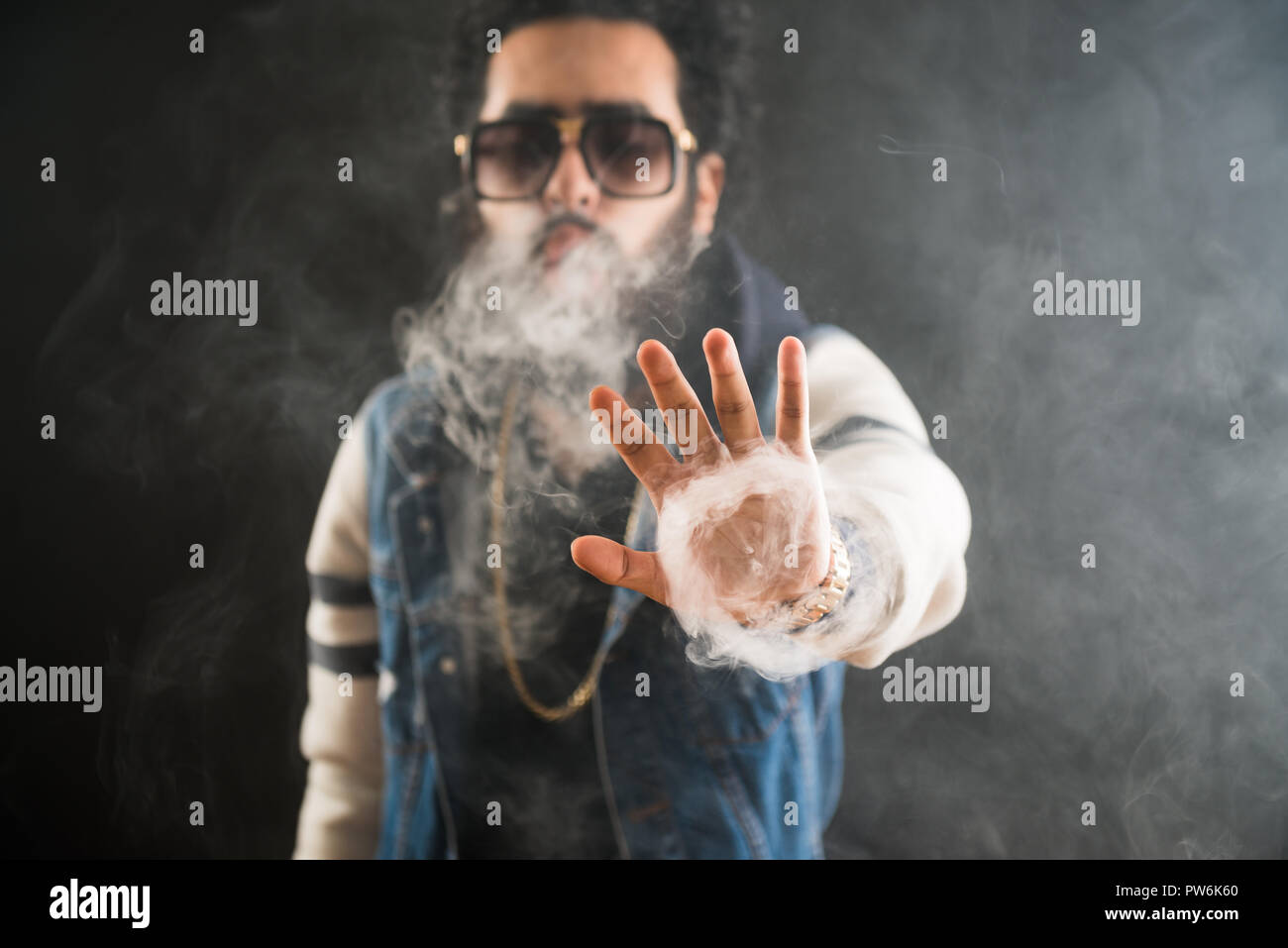 Smoking vape. vaping man holding a mod. Vape Rings. A man launches a ring of smoke. Tricks with smoke. Stock Photo