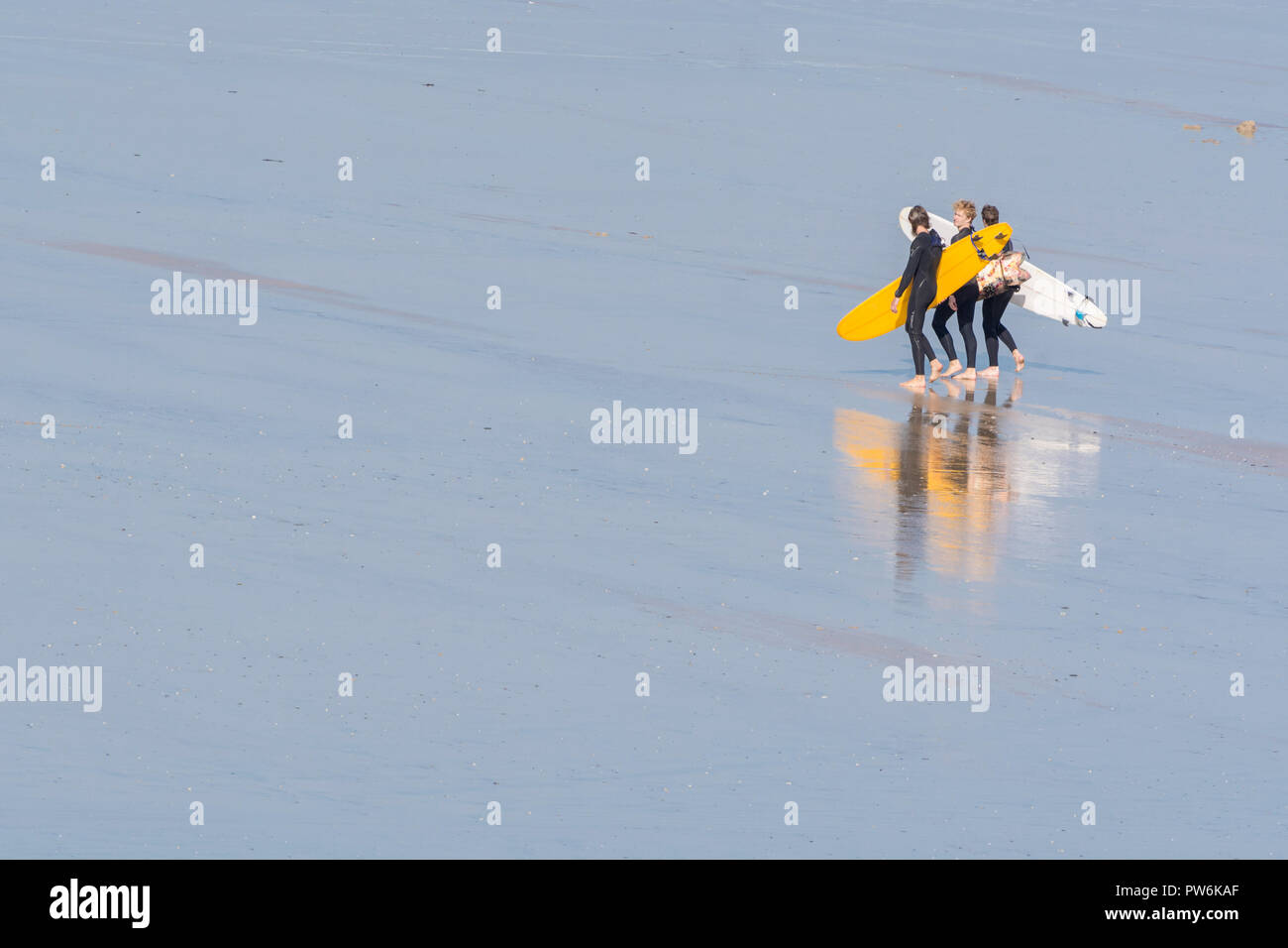 Surfers at Newquay, Cornwall, carrying surfboards on beach - home of Boardmasters Festival. Stock Photo