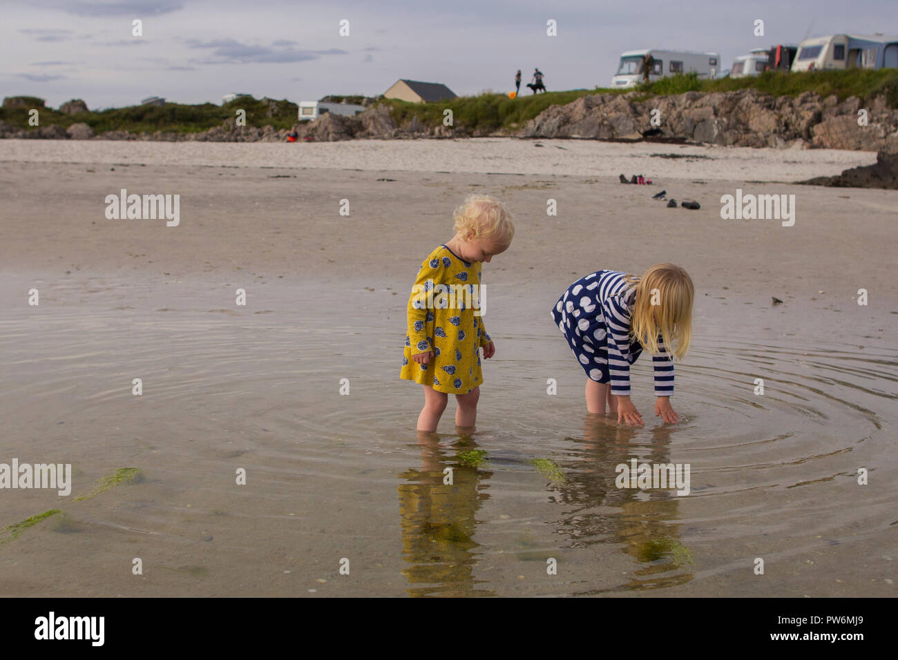 Young girl playing and exploring a sandy beach on a hot summers day in Scotland Stock Photo