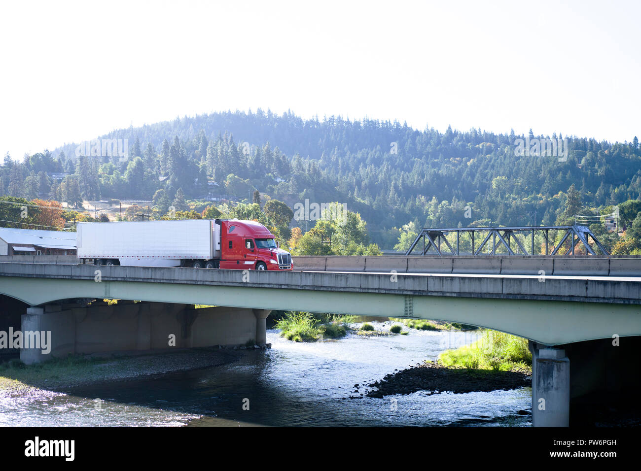 Modern red big rig semi truck with reefer semi trailer transporting ...