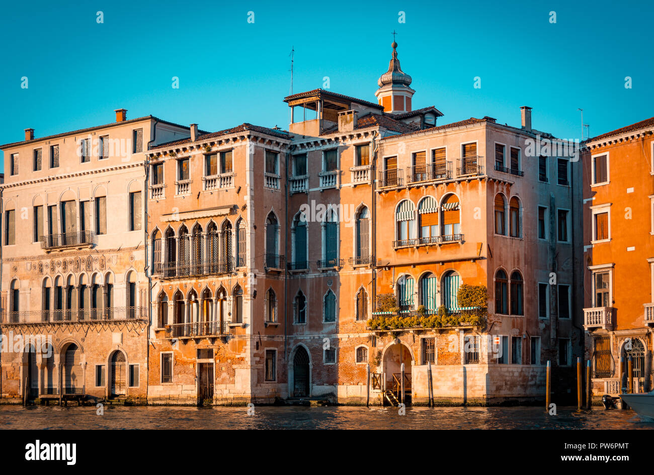 Ancient palaces in Grand canal waters of Venice Italy. Orange and teal view. Stock Photo
