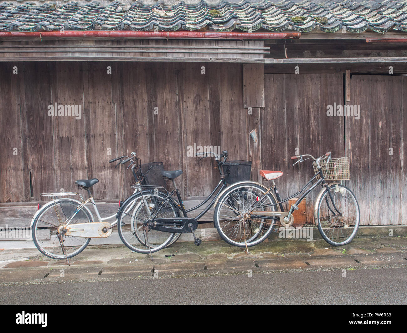 Trio 3 bikes, tile roof and wooden wall, neighbourhood street, Muroto, Kochi, Shikoku, Japan Stock Photo