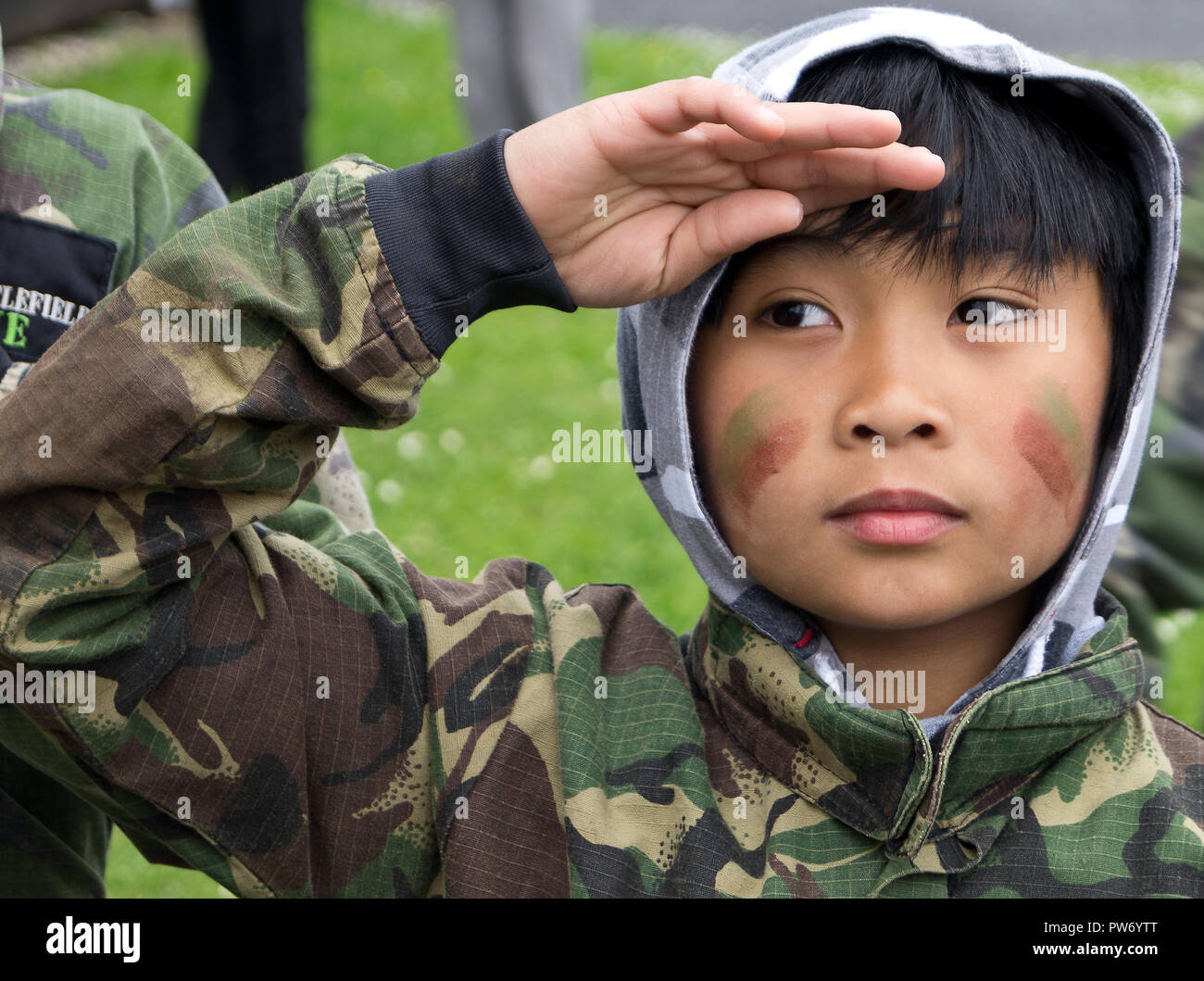 Close up photo of Asian Boy saluting in camouflage uniform. Stock Photo