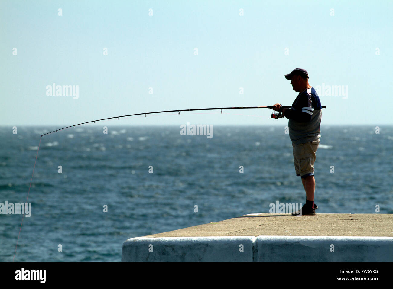 Man sea fishing on a pier in Sami, Kefalonia, Greece Stock Photo