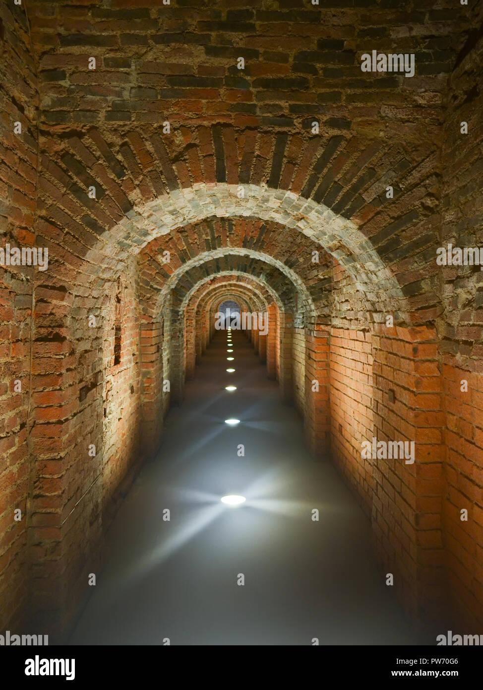 Dark brick long mystical arched corridor illuminated in the floor. Catacombs of Peter-Pavel's Fortress in St. Petersburg Stock Photo