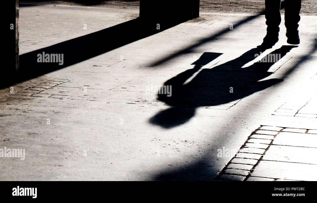 Silhouette shadows of a person walking in city street passage in black ...