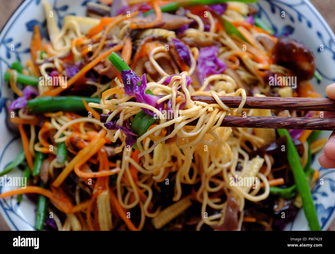 Fry noodles mixed vegetables, a Vietnamese vegetarian dish for vegans, with colorful greens, vermicelli and mushrooms, quick to  make for breakfast at Stock Photo