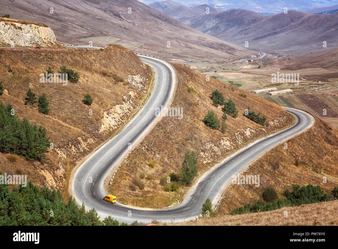 Yellow car driving on mountain serpentine, Armenia Stock Photo