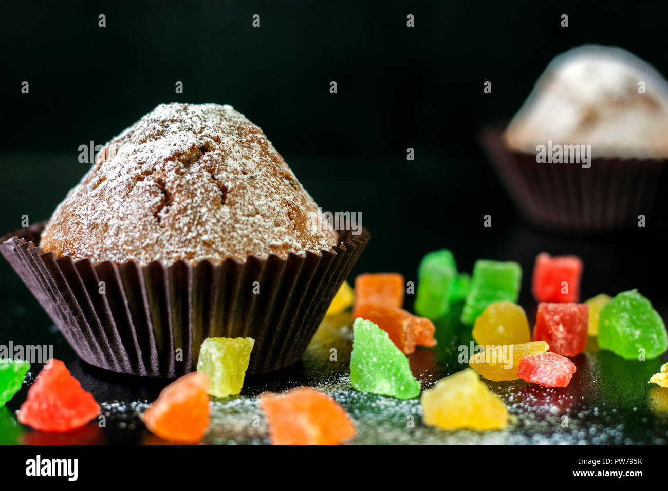 Freshly baked muffins with candied fruit on a black table Stock Photo