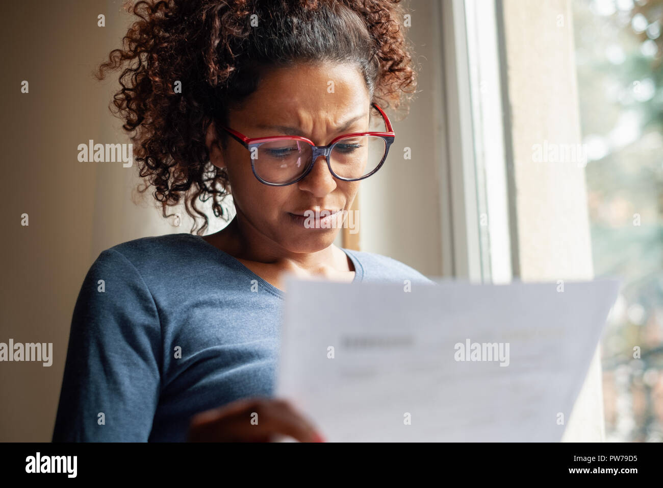 Portrait of worried black woman standing beside window Stock Photo