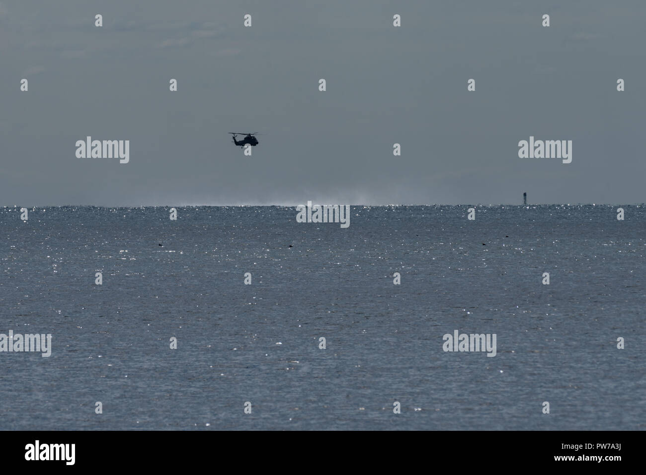 Helicopter practicing rescue manoeuvres on Long Island Sound with prop wash visible Stock Photo