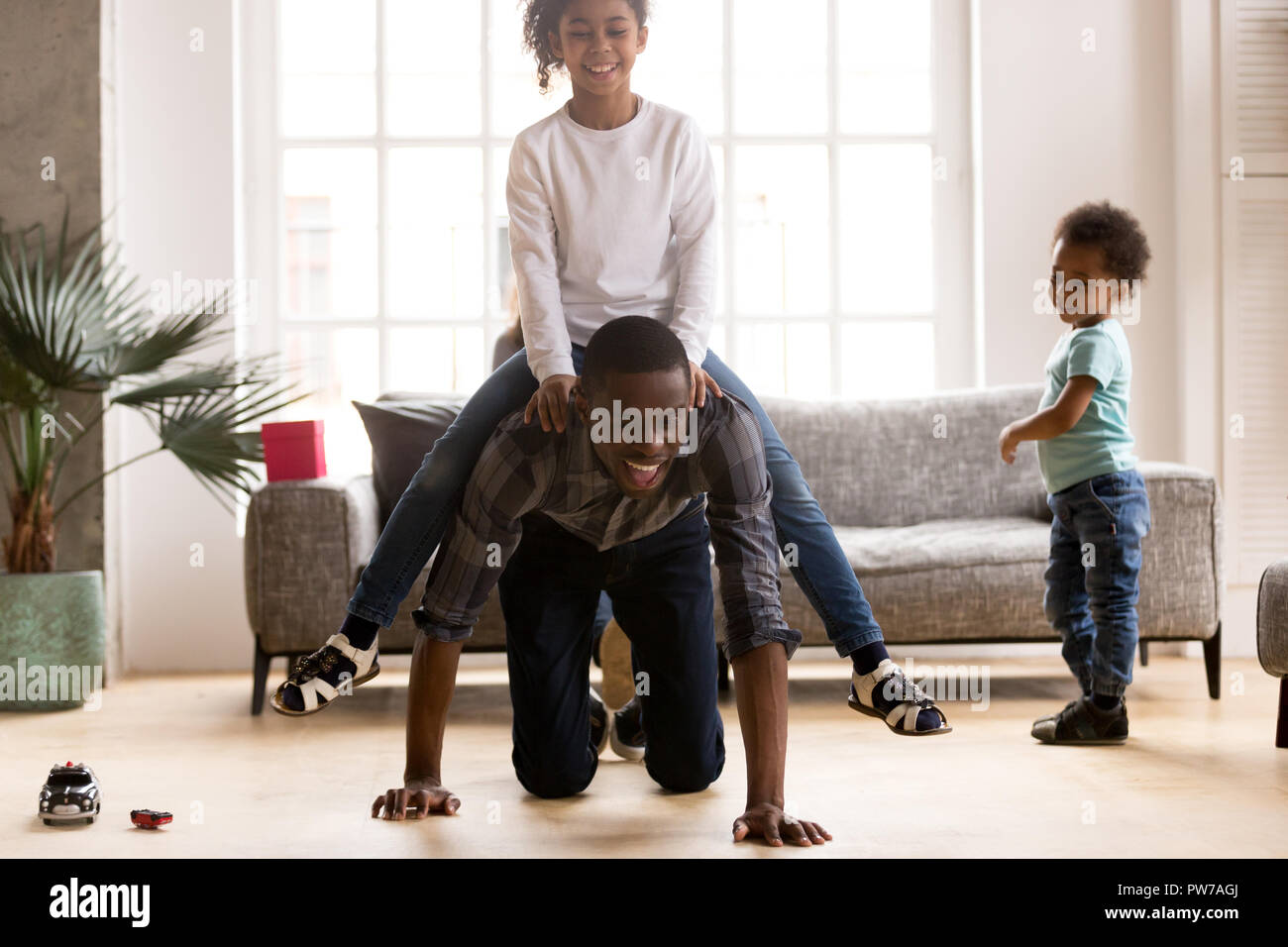 Black playful father ride daughter on his back indoors Stock Photo
