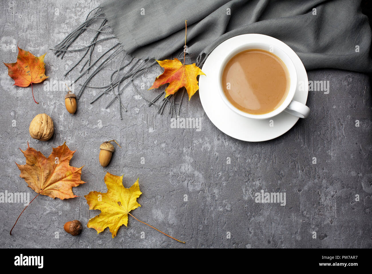 Autumn composition. Cup of coffee, blanket, autumn leaves on grey background. Flat lay. Stock Photo