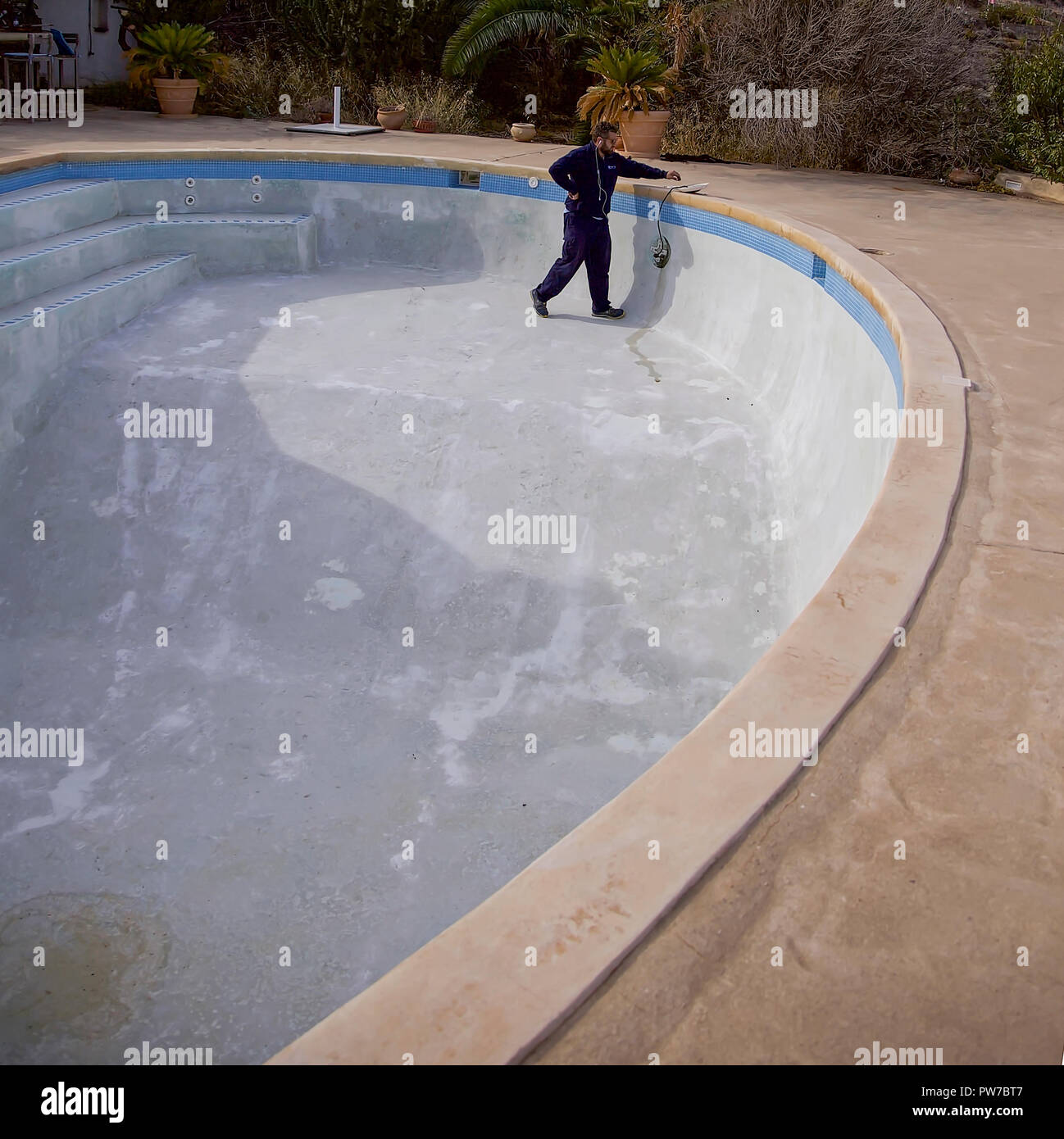 Man working on  repairing lights in a  empty swimming pool. Editorial Image. Stock Photo