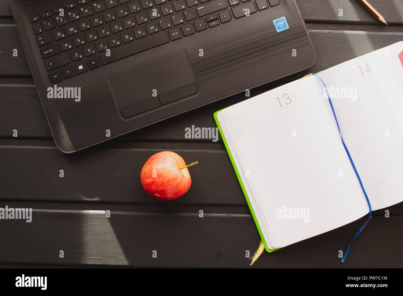 Working environment Netbook with a notebook are on the table. Next is a red apple Stock Photo