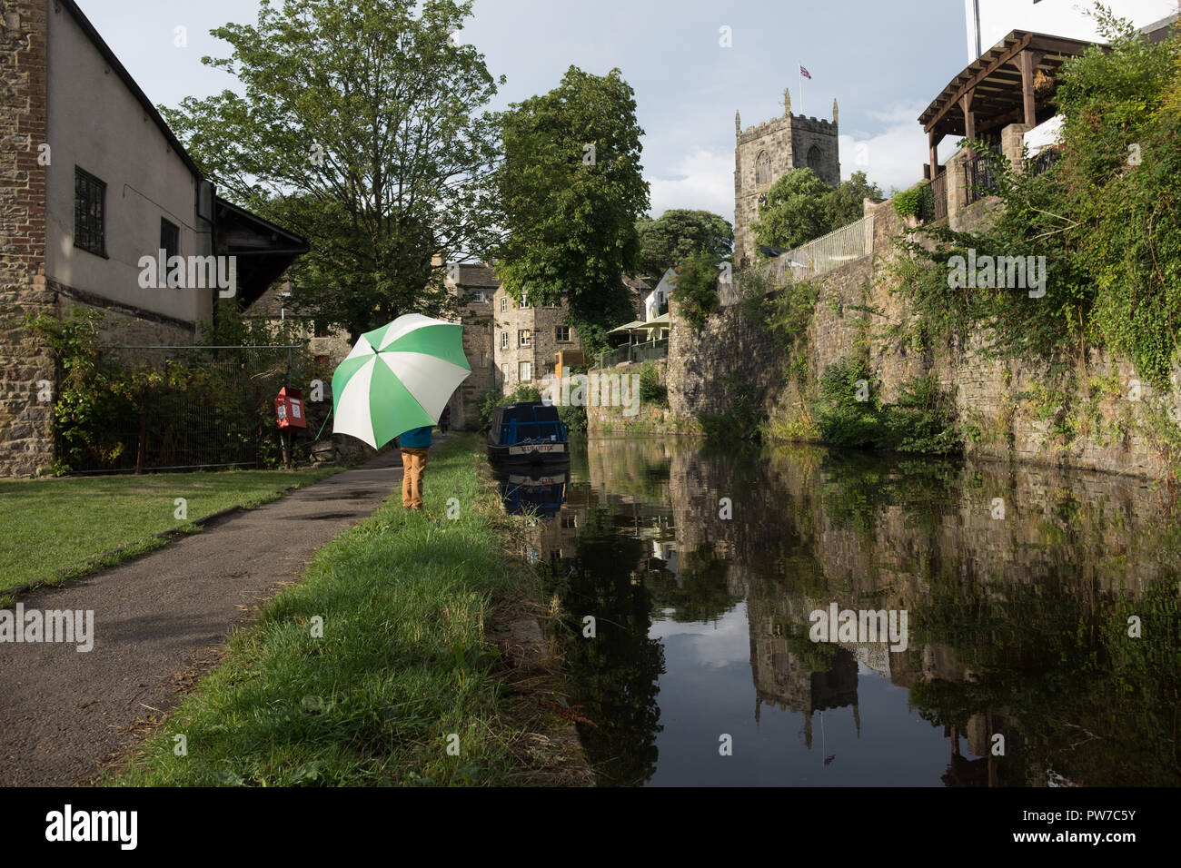 Child with umbrella standing next to the Leeds Liverpool canal in Skipton, England. Stock Photo