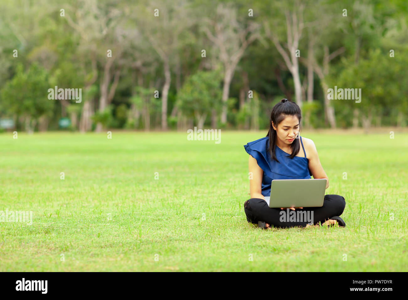 Portrait of beautiful young asian woman sitting on green grass field ...