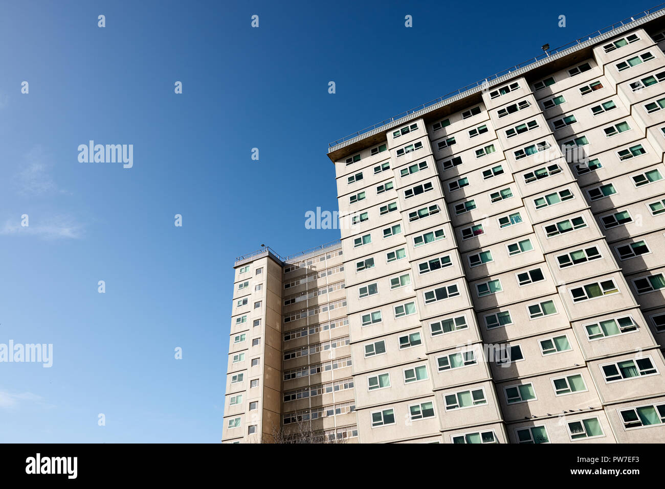 Social housing apartment tower block against a blue sky. Stock Photo