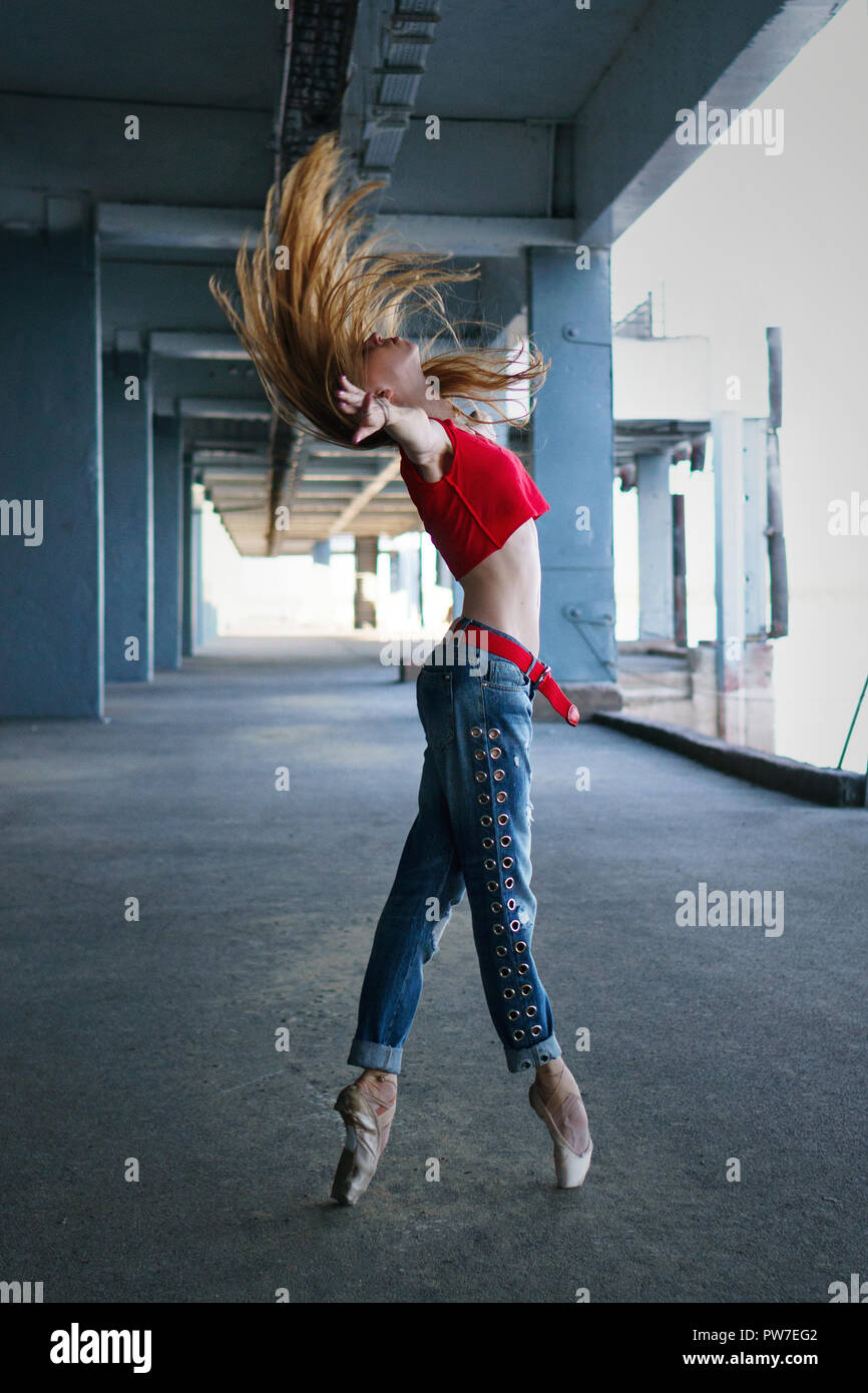 Ballerina dancing in jeans, t-shirt and pointe. Street performance. Modern  ballet. Slender girl stand on tiptoe. Red hair fly Stock Photo - Alamy