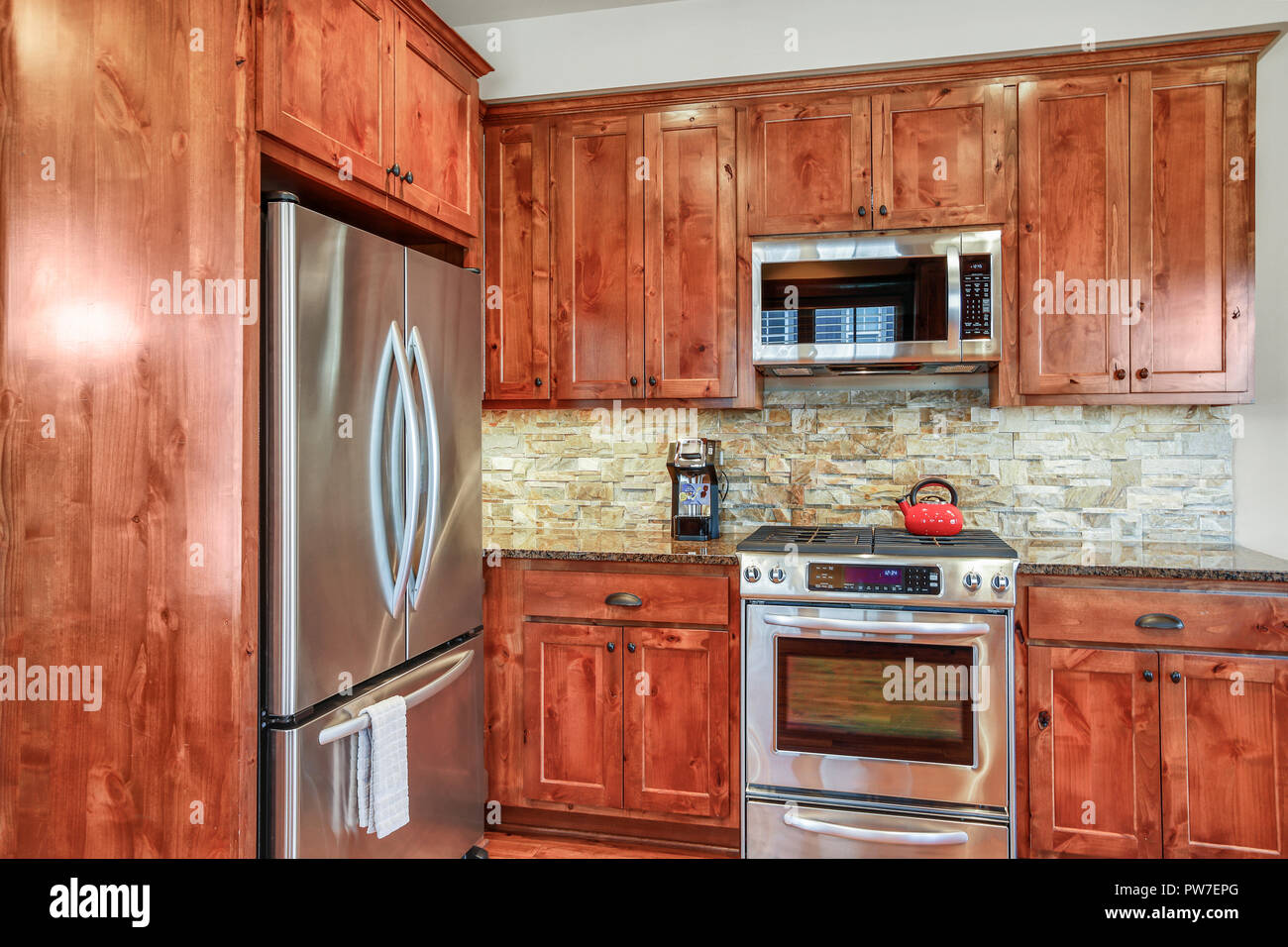 Wooden kitchen room with stone backsplash, granite countertops and stainless steel appliances. Northwest, USA Stock Photo