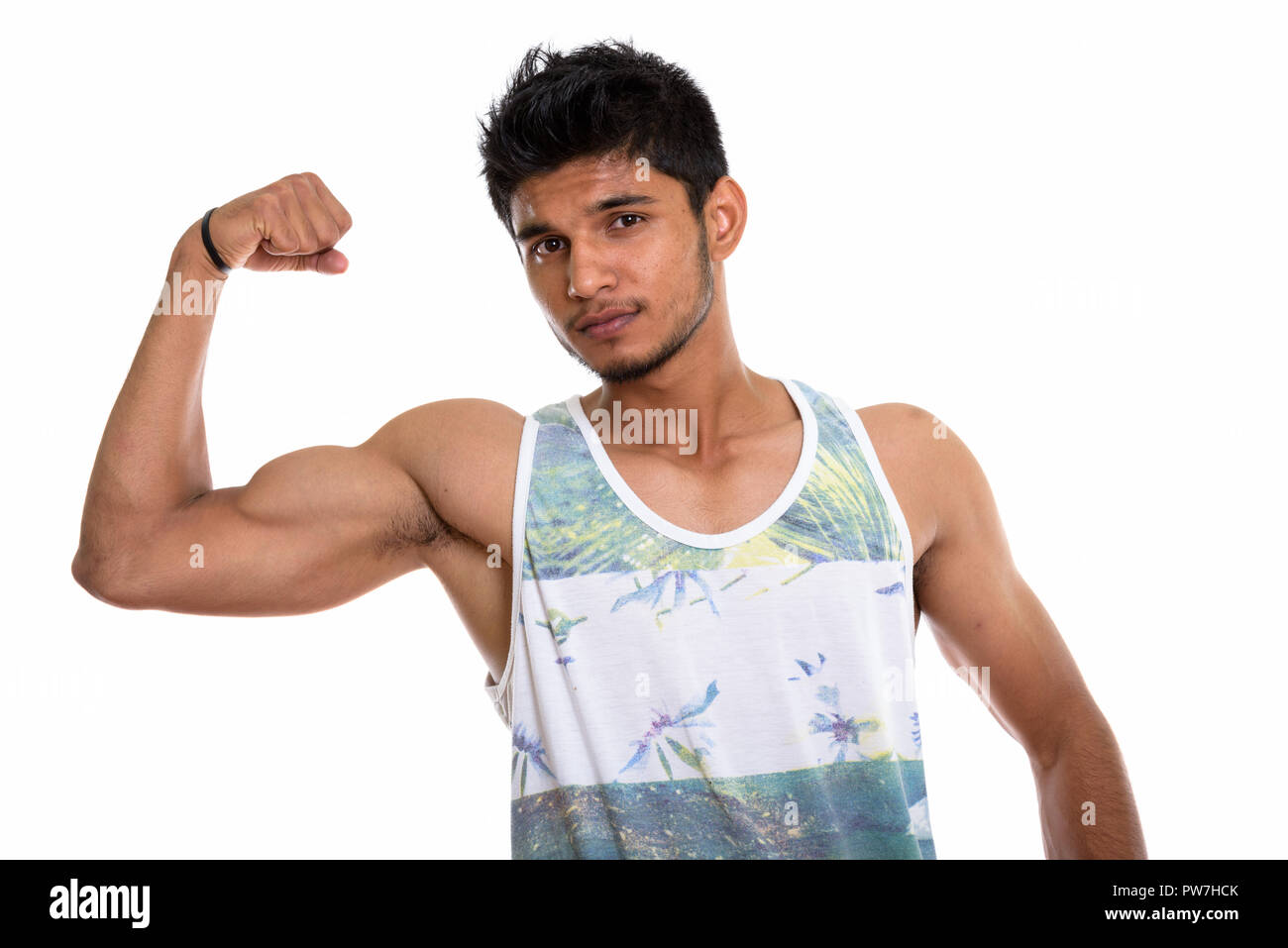 Studio shot of young handsome Indian man flexing his arm Stock Photo