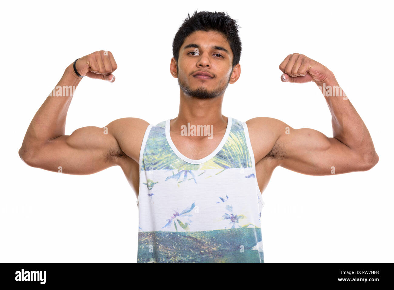 Studio shot of young handsome Indian man flexing both arms Stock Photo