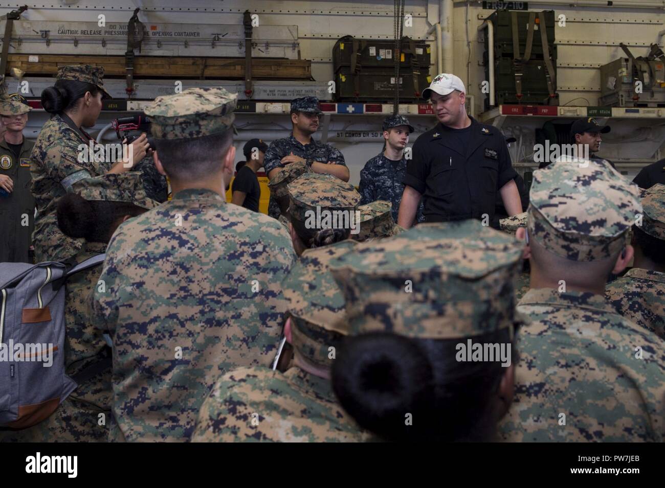 WHITE BEACH, Okinawa (Sept. 21, 2017) Quartermaster 1st Class Matthew Lenerville, from Richardton, N.D., gives a safety brief to Marine Corps Junior ROTC students from Kubasaki High School during a tour of the amphibious assault ship USS Bonhomme Richard (LHD 6). Bonhomme Richard, flagship of the Bonhomme Richard Amphibious Ready Group, is operating in the Indo-Asia-Pacific region to enhance partnerships and be a ready-response force for any type of contingency. Stock Photo